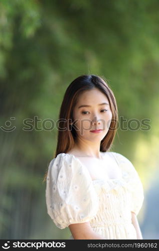 Beautiful young woman with white dress on bamboo forest background