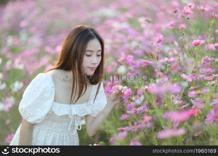 Beautiful young woman with white dress on pink cosmos flowers background