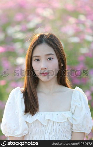 Beautiful young woman with white dress on pink cosmos flowers background