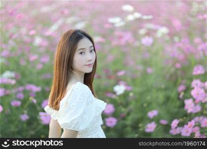 Beautiful young woman with white dress on pink cosmos flowers background