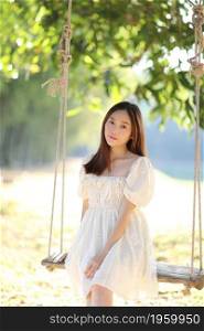 Beautiful young woman with white dress on swing