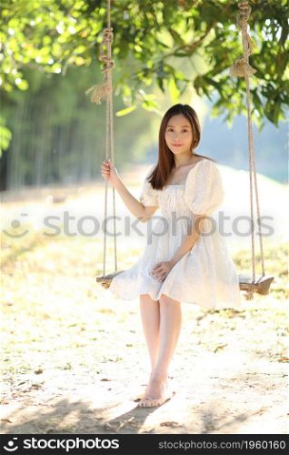 Beautiful young woman with white dress on swing