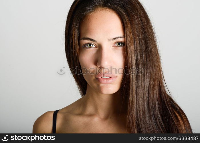 Beautiful young woman without make-up. Beautiful girl with green eyes, model of fashion wearing black tank top on white background.