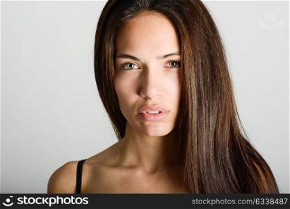 Beautiful young woman without make-up. Beautiful girl with green eyes, model of fashion wearing black tank top on white background.