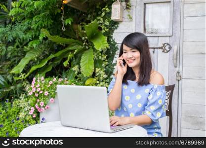 Beautiful young woman working on computer and talking on phone