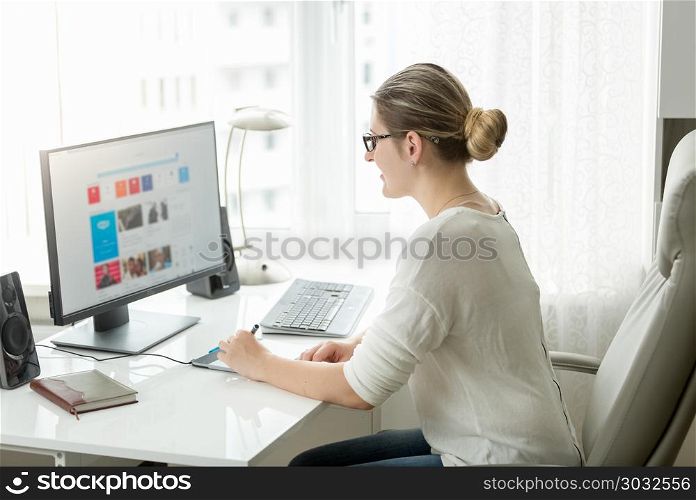 Beautiful young woman working on computer at office with big window. Beautiful woman working on computer at office with big window