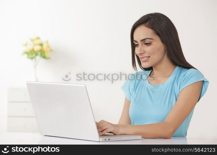 Beautiful young woman working on laptop at home