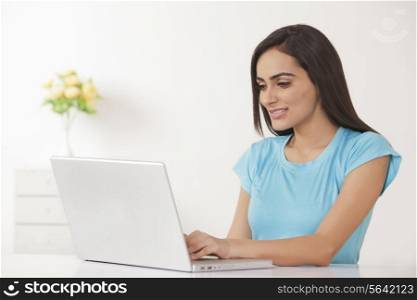 Beautiful young woman working on laptop at home