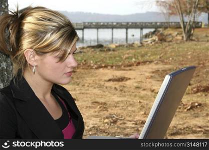 Beautiful young woman working on laptop computer at the park.