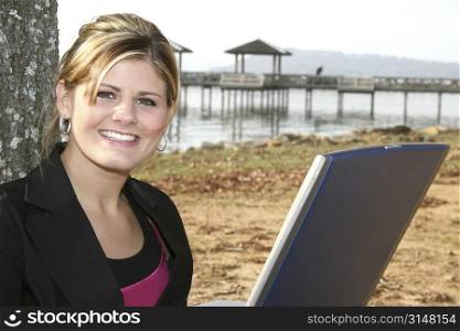 Beautiful young woman working on laptop computer at the park.