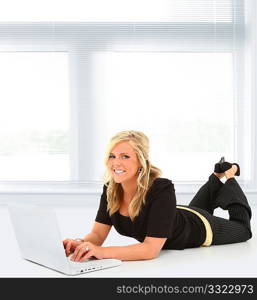 Beautiful young woman working on laptop in school or office on floor with copy space.