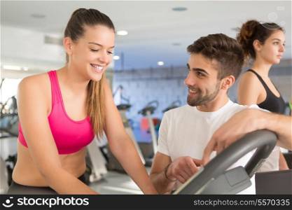 Beautiful young woman working out at the gym with the help of her personal trainer