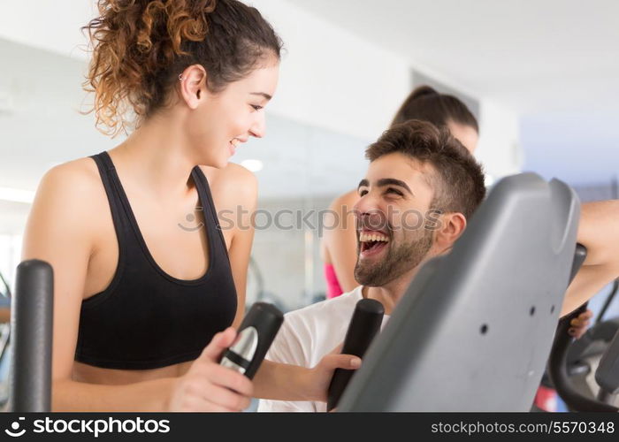 Beautiful young woman working out at the gym with the help of her personal trainer