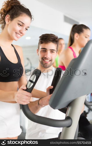 Beautiful young woman working out at the gym with the help of her personal trainer