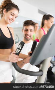 Beautiful young woman working out at the gym with the help of her personal trainer