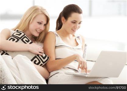 Beautiful Young Women Surfing the Internet Online on Laptop, Sitting on the Sofa in Living Room