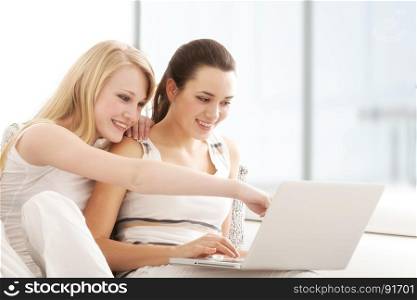 Beautiful Young Women Surfing the Internet Online on Laptop, Sitting on the Sofa in Living Room