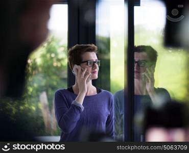 beautiful young women using mobile phone by the window of her luxury home