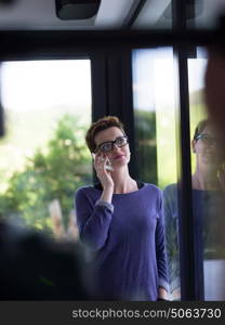 beautiful young women using mobile phone by the window of her luxury home