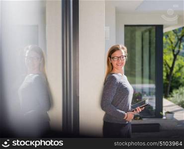 beautiful young women using tablet computer in front of her luxury home villa