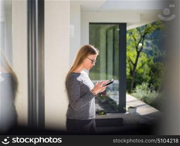 beautiful young women using tablet computer in front of her luxury home villa