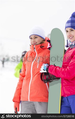 Beautiful young women with snowboard looking away