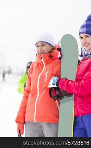 Beautiful young women with snowboard looking away