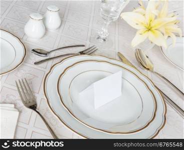 Beautifully decorated table with white plates, crystal glasses, cutlery and flowers on luxurious tablecloths, with guest card