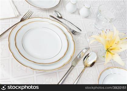 Beautifully decorated table with white plates, crystal glasses, cutlery and flowers on luxurious tablecloths