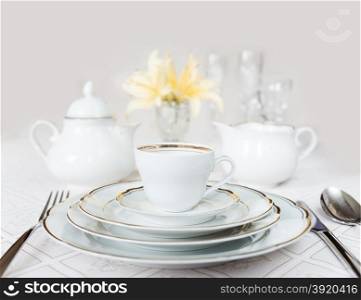Beautifully decorated table with white plates, crystal glasses, linen napkin, cutlery and lily flowers on luxurious tablecloths