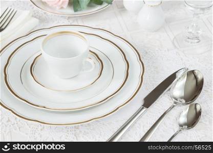 Beautifully decorated table with white plates, crystal glasses, linen napkin, cutlery and rose flowers on luxurious tablecloths