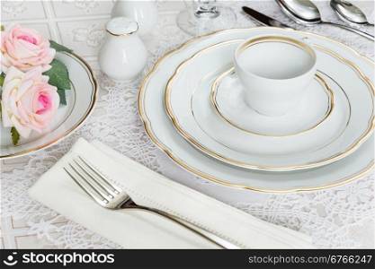 Beautifully decorated table with white plates, crystal glasses, linen napkin, cutlery and rose flowers on luxurious tablecloths
