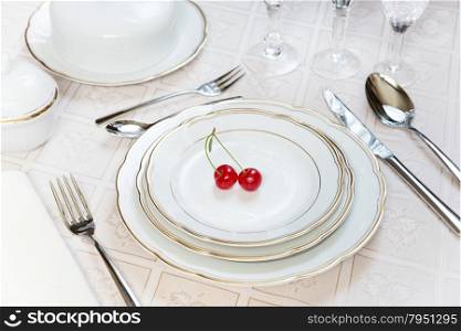 Beautifully decorated table with white plates, crystal glasses, linen napkin, cutlery and tulip flowers on luxurious tablecloths