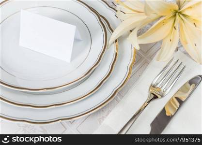 Beautifully decorated table with white plates, crystal glasses, linen napkin, cutlery and flowers on luxurious tablecloths, with guest card