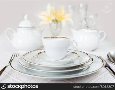 Beautifully decorated table with white plates, crystal glasses, linen napkin, cutlery and lily flowers on luxurious tablecloths