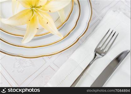 Beautifully decorated table with white plates, linen napkin, cutlery and flowers on luxurious tablecloths