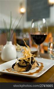 Beautifully plated salmon fillet garnished with shataki mushrooms and onions. Served on a white plate with a brown ginger sauce. There is a glass of red wine on the table as well.. Commercial Photography