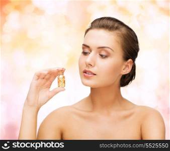 beauty and cosmetology concept - beautiful woman showing bottle with golden dust