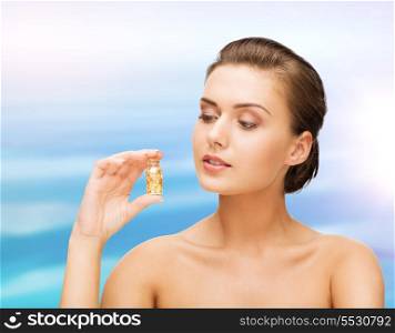 beauty and cosmetology concept - beautiful woman showing bottle with golden dust