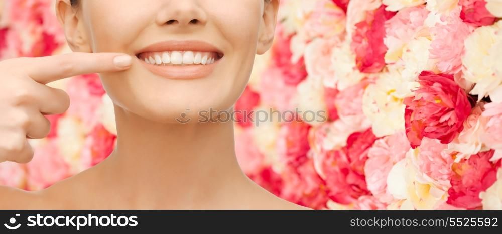 beauty and dental health concept - closeup picture of beautiful woman pointing finger to her teeth