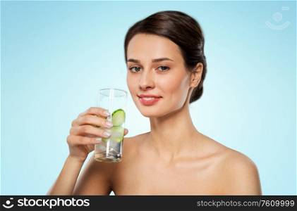 beauty and detox concept - woman drinking fresh water with cucumber and ice over blue background. woman drinking water with cucumber and ice