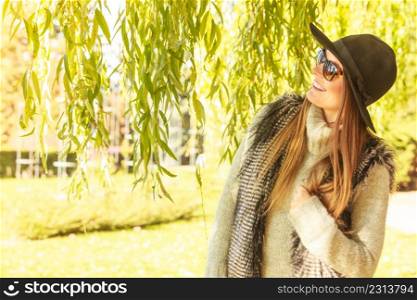 Beauty and fashion of women. Young attractive fashionable girl wearing stylish hat waistcoat and sunglasses. Pretty woman around leaves of willow tree.. Adorable woman in sunglasses