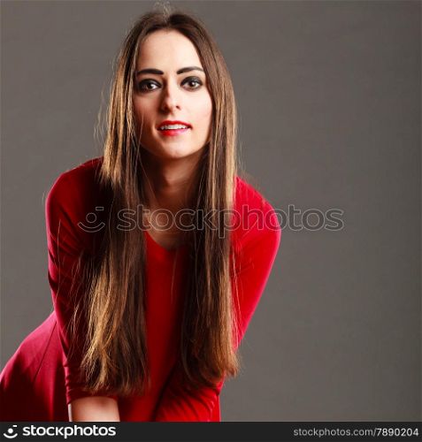 Beauty and fashion. Woman portrait. Attractive young female in red on gray background in studio.
