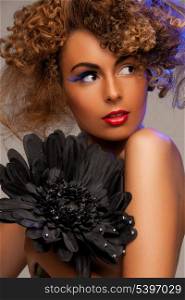 beauty and glamour concept - woman with long curly hair and big black flower