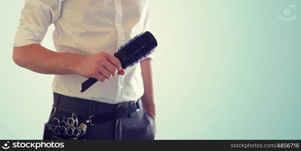 beauty and hair salon, hairstyle and people concept - close up of male stylist with brush blank over blue background