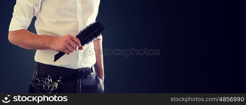 beauty and hair salon, hairstyle and people concept - close up of male stylist with brush at salon over blank black background