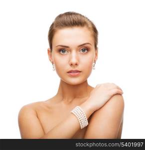 beauty and jewelery concept - beautiful woman with pearl earrings and bracelet