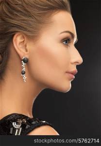 beauty and jewelery concept - woman wearing shiny diamond earrings