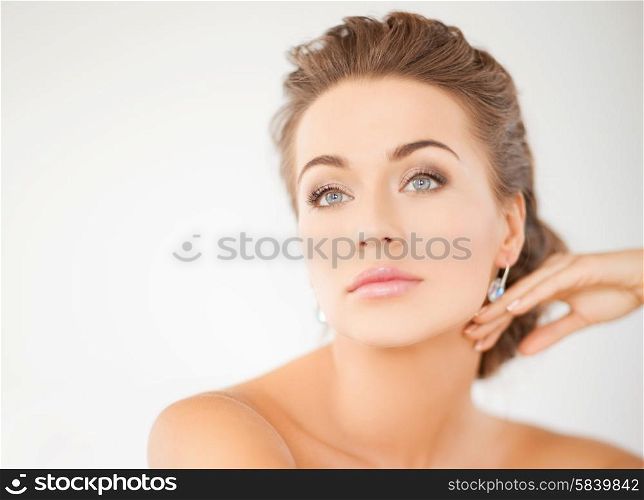 beauty and jewelery concept - woman wearing shiny diamond earrings. woman wearing shiny diamond earrings