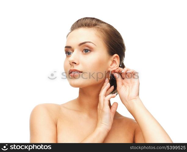 beauty and jewelry concept - beautiful woman trying on gold earrings